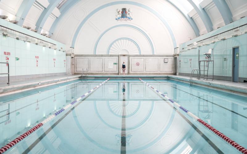 A woman standing at the far end of a swimming pool facing the camera