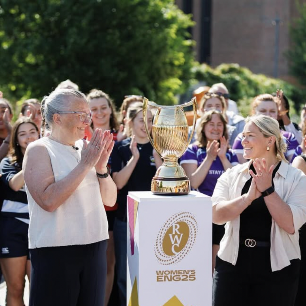 trophy for rugby world cup with women clapping around it 