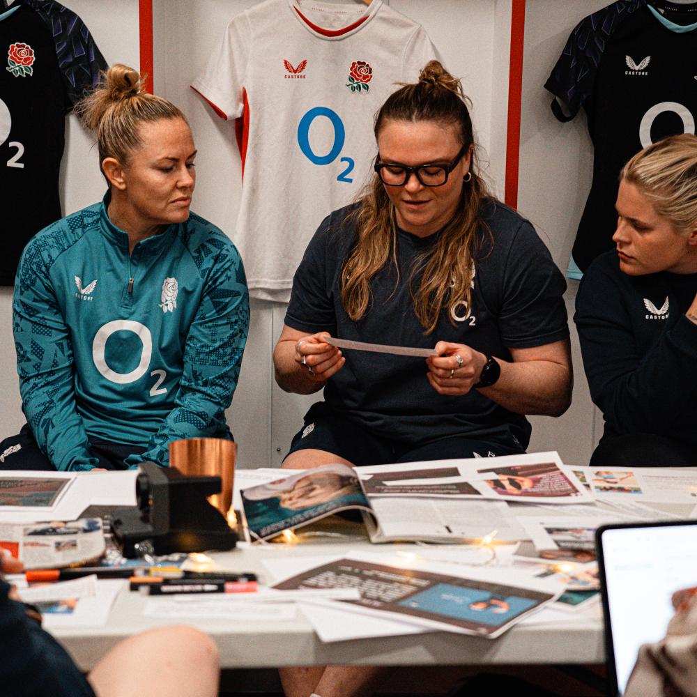 Rugby players at a table  in the dressing room, taking part in a creative workship