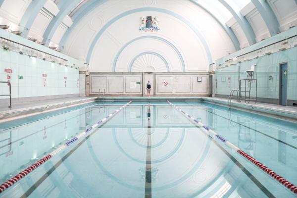 A woman standing at the far end of a swimming pool facing the camera