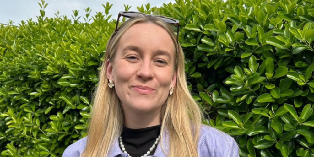 ellen stands in front of a green bush